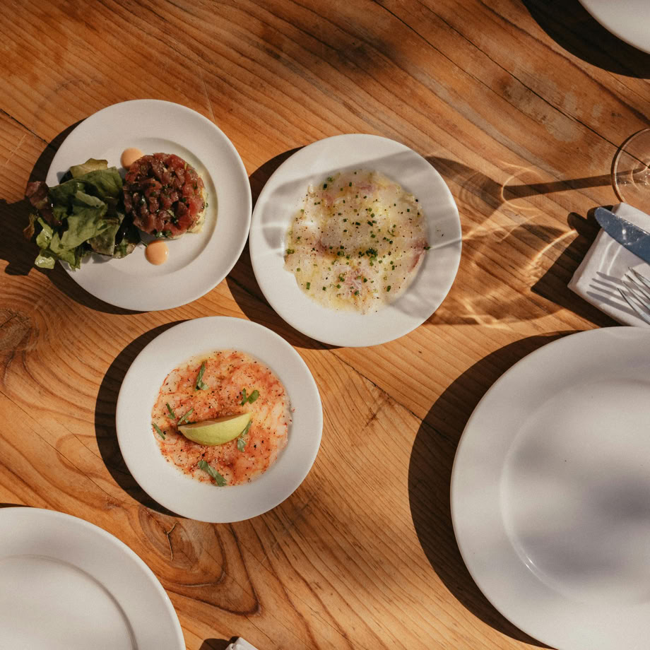 Aerial view of a rustic dining table with elegant appetizers and white plates.
